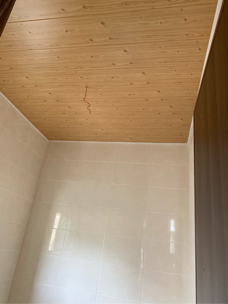 1) 照片顯示一個浴室的一部分，包括木紋天花板和部分白色磁磚牆