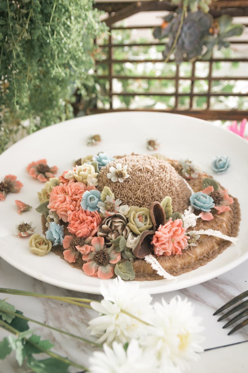 這張「花朵蛋糕」的照片是一個以棕色糕點為底，上面用許多色彩繽紛的花朵裝飾的甜點。