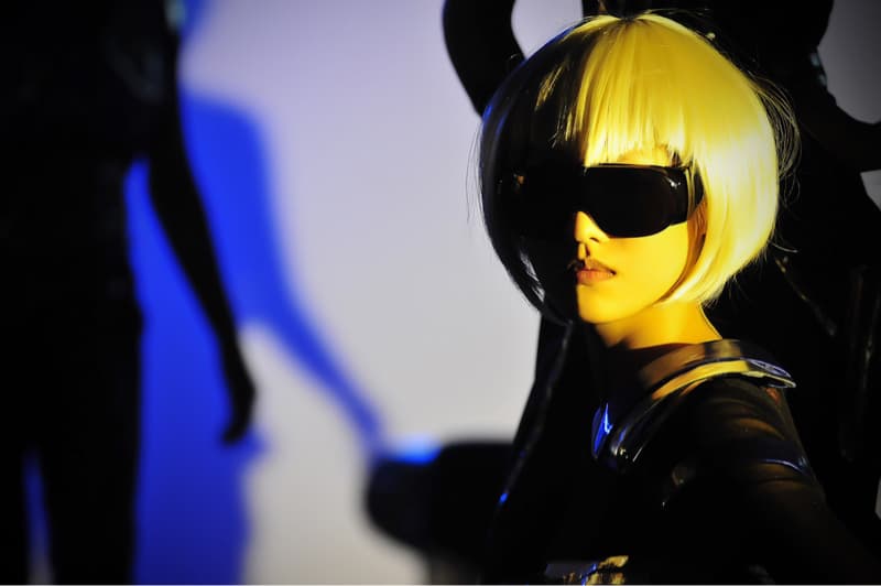 這張照片是一個戴著墨鏡和金黃色短髮的女孩，她穿著一件黑色的衣服，並且用銳利的眼神看著鏡頭。