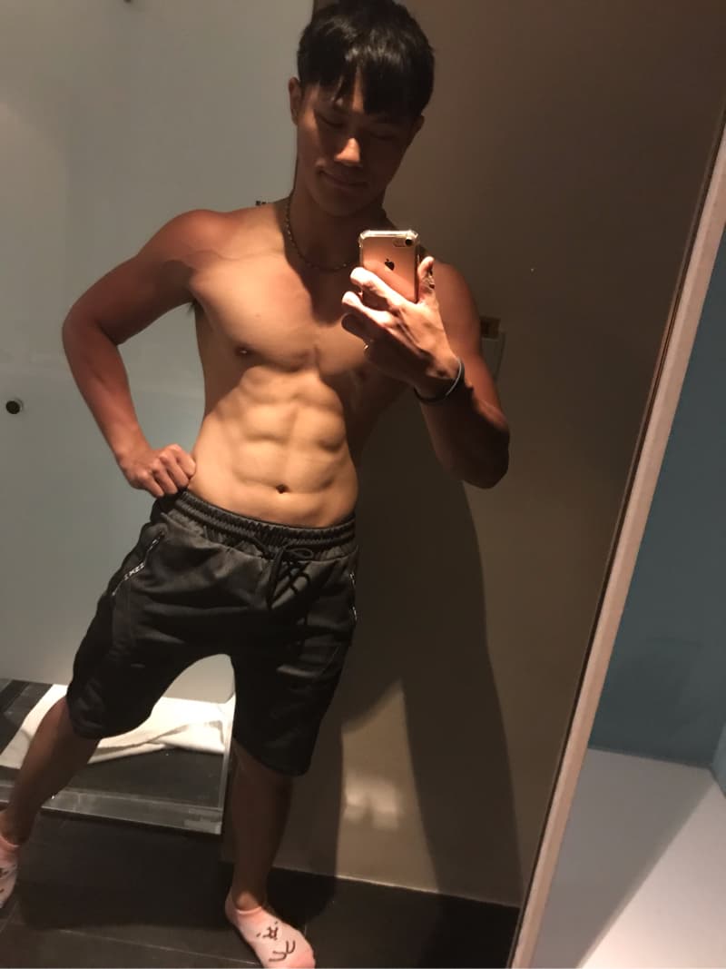 這張「健身房自拍」的照片是，一位穿著黑色運動短褲的年輕男子，在鏡子前自拍，他露出健美的腹肌。