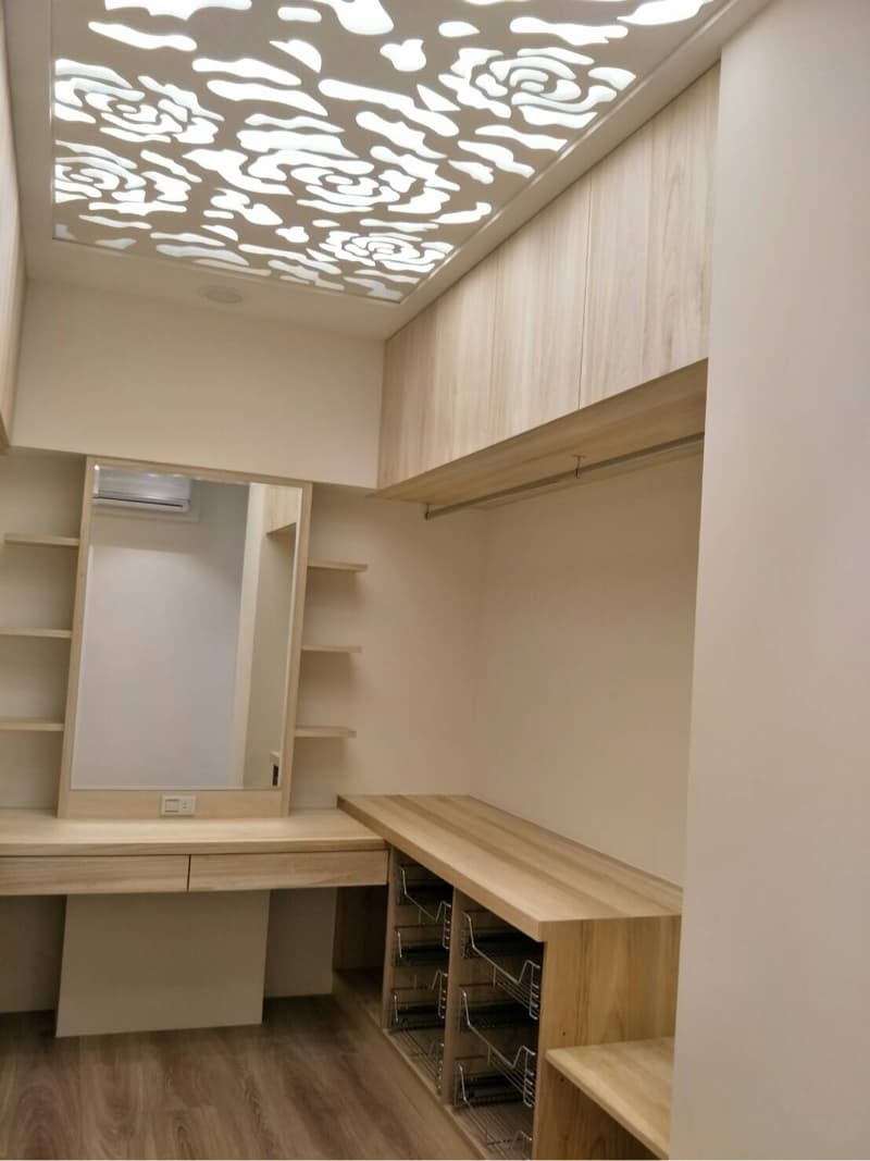 這張照片是臥室衣櫃上方設計，以木質櫃體結合鏤空花紋天花板，營造出簡約、時尚的空間氛圍。