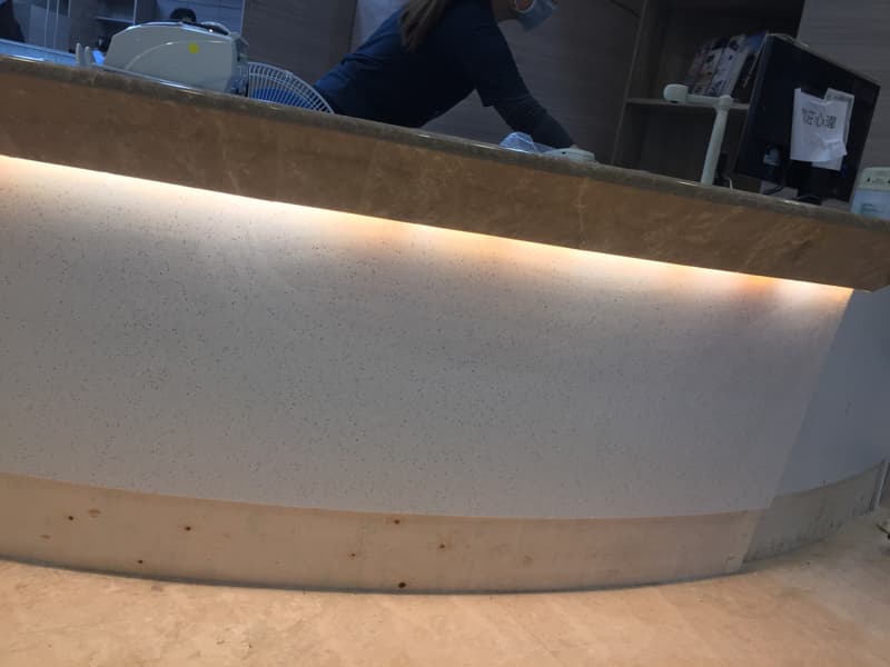 這張照片是服務台的櫃台，上面有條細長的燈光，照亮了櫃台，讓櫃台看起來更明亮乾淨。