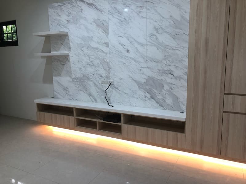 這張照片是一張電視櫃的照片，電視櫃下方有裝設燈條，燈光柔和，讓整體空間看起來更溫暖舒適。