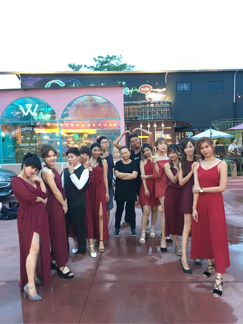 這張照片是一群穿著紅色禮服的年輕女子站在街頭，她們在一家咖啡店前面合影。