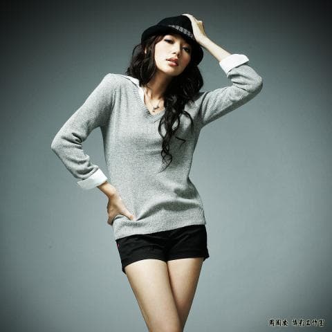 這張照片是一個戴著帽子、穿著灰色毛衣和黑色短褲的年輕女性。