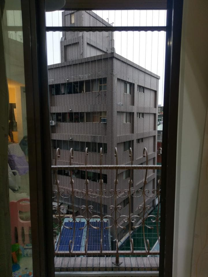 1) 照片顯示一個帶有鐵欄杆的窗戶,透過窗戶可以看到一棟建築物
