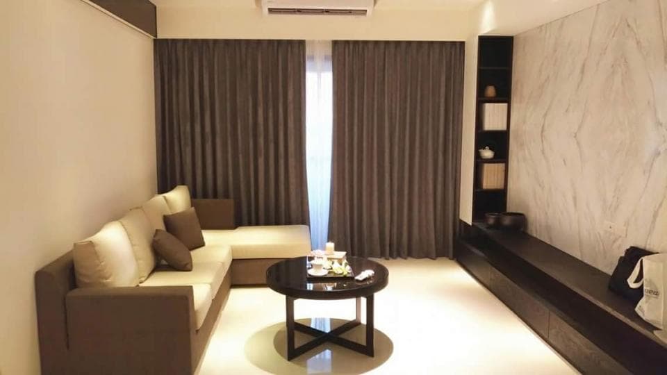 1) 照片顯示一個現代化的客廳,有著一張深棕色的沙發、一個茶几,以及一面白色的牆壁