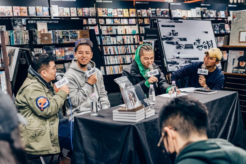 這張「書店」的照片是四個年輕人在書店裡,他們坐在桌子旁,其中兩個人手裡拿著麥克風。