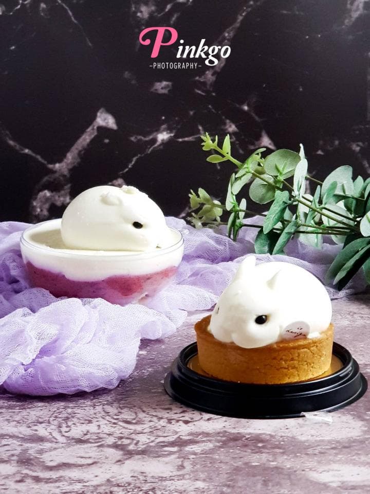 這張照片是兩個兔子形狀的甜點,一個是放在玻璃杯中,另一個是放在黑色圓盤上。