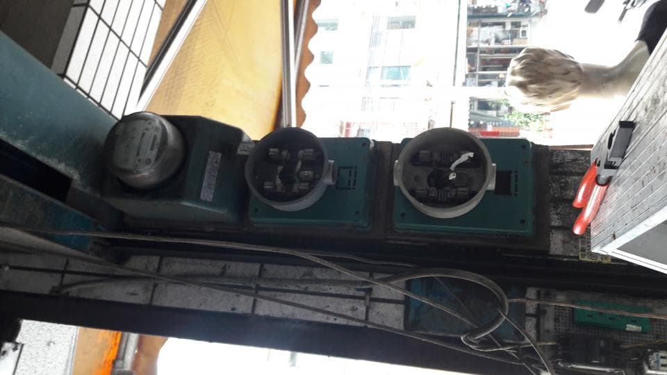 1) 照片中顯示三個綠色電錶箱,安裝在建築物的外部牆壁上