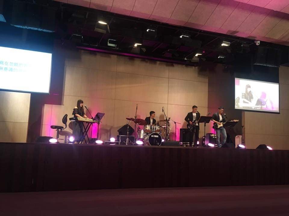 這張「舞臺表演」的照片是一個樂隊正在演奏,他們包括一名女鍵盤手,兩名吉他手和一名鼓手,舞臺上還有音響設備。