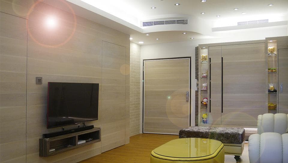 這張照片是一間客廳,最重要的是電視牆,電視牆上有一個現代化的電視機,底下有一個木質的電視櫃,上面放著電視機和一些裝飾品。