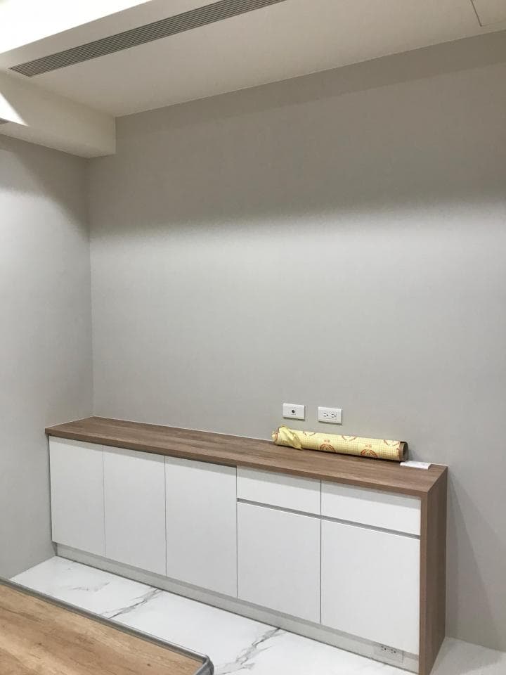 1) 照片顯示一個白色櫥櫃,櫃子上面放了一卷壁紙,牆壁和天花板都是白色