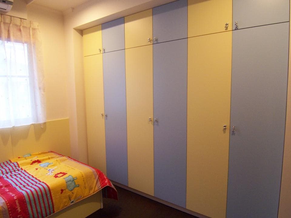 這張照片是一間臥室,房間裡有床和一個大型的衣櫃,衣櫃的門是藍色和黃色的。