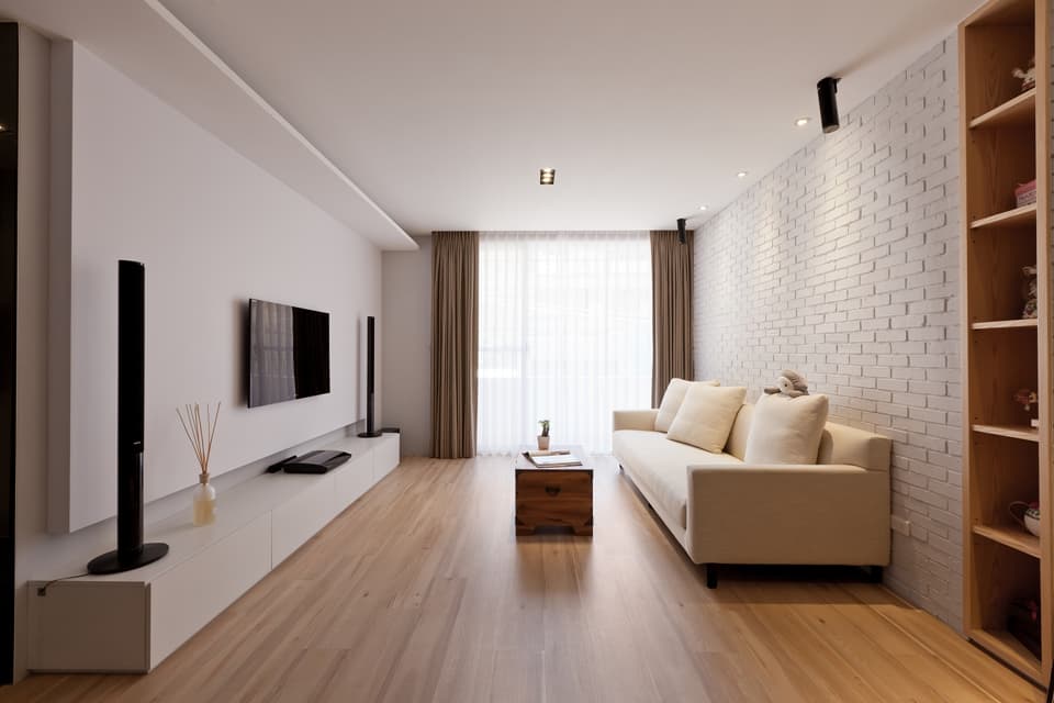 這張「現代化客廳」的照片是,一張白色沙發靠牆擺放,前方有一張小茶几,左側是電視牆,牆上掛著電視和音響,牆下是白色電視櫃。