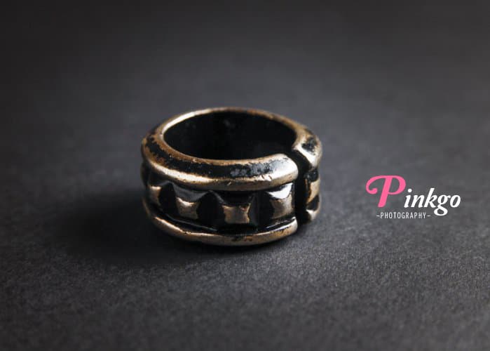 這張照片是一個金屬戒指,它有著黑色的底座和金色的紋路,看起來很精緻。