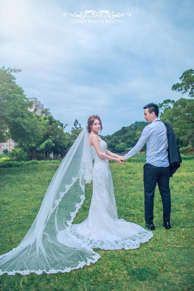 這張「婚禮」的照片是一對新人,新郎穿著白色襯衫和西裝外套,新娘穿著白色婚紗和頭紗,他們在綠色的草地上牽手,看起來非常甜蜜幸福。