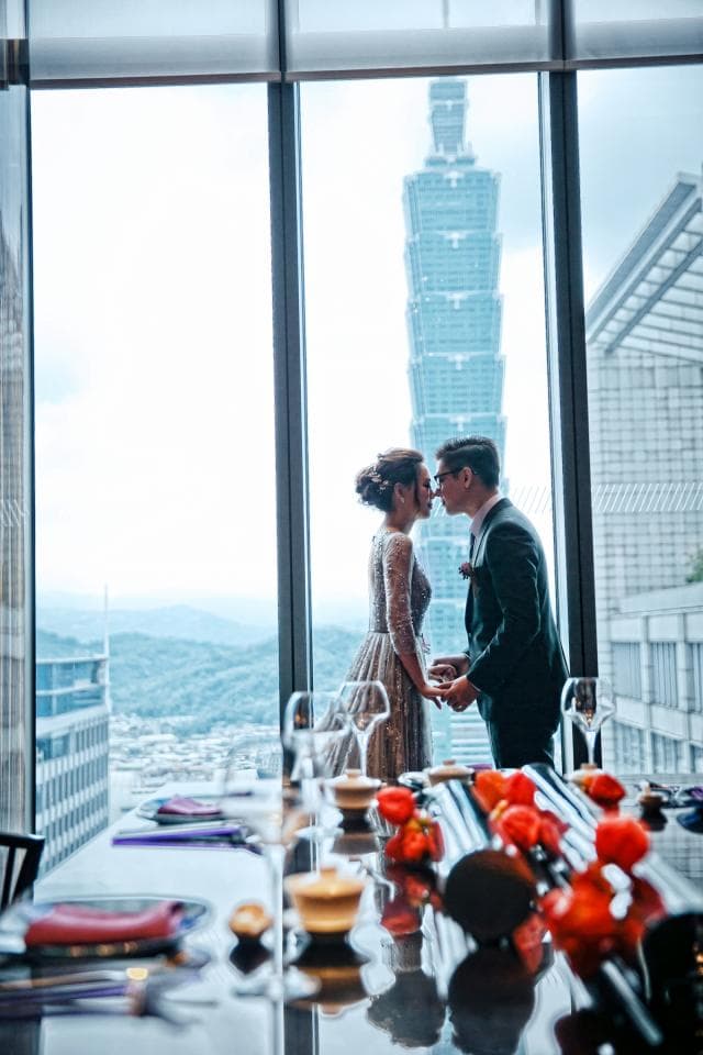 這張「婚禮」的照片是新人站在窗邊,背景是臺北101,桌上擺滿了喜慶的紅色裝飾。