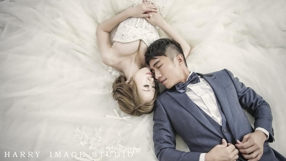 這張照片是一對新人在婚紗照中互相依偎著,新娘穿著白色的婚紗,新郎穿著深藍色的西裝,兩人的臉頰相貼,展現出甜蜜幸福的愛情。