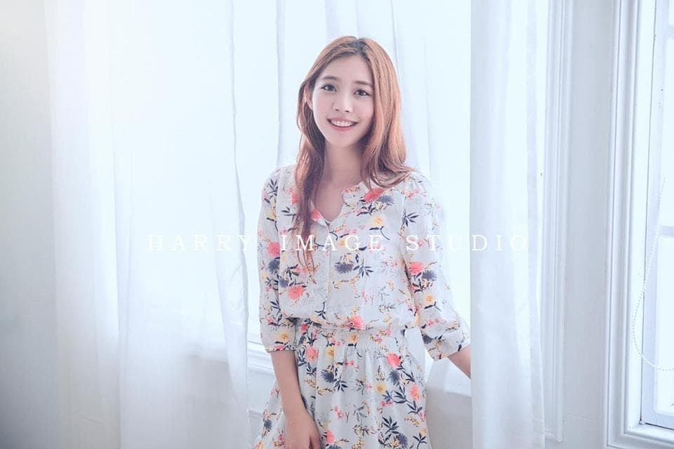 這張「室內」的照片是一個穿著白色印花連衣裙的女孩,站在窗戶前,背對著光,微笑著看著鏡頭。