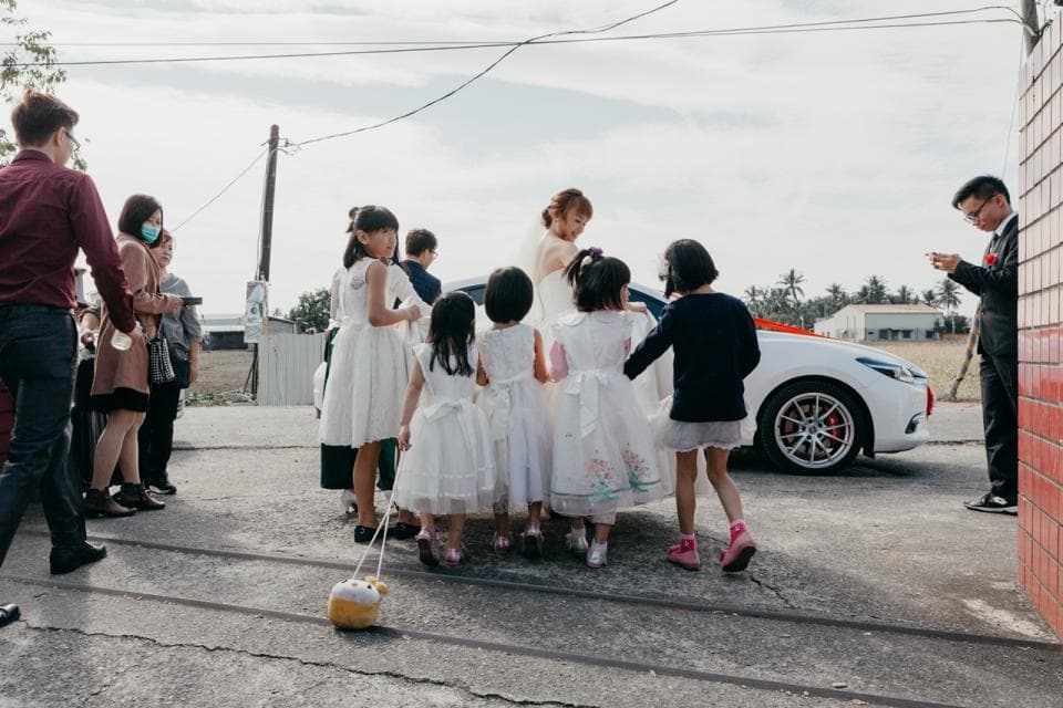 這張「婚禮」的照片是幾位小朋友在婚禮現場,新郎在旁邊看著,新娘和伴娘在車旁。