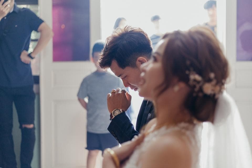 這張照片是一對新人婚禮的畫面,其中新郎正在深情地向新娘低頭,新娘則露出幸福的笑容,臉上洋溢著甜蜜。