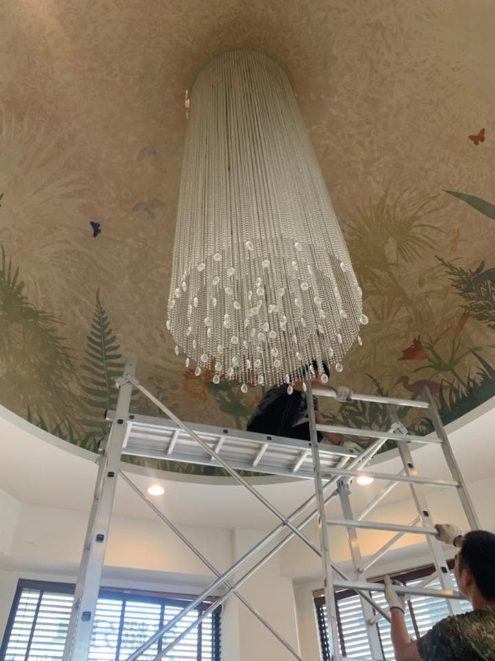 1) 照片顯示一個工人站在鷹架上,正在修理一個大型的水晶吊燈