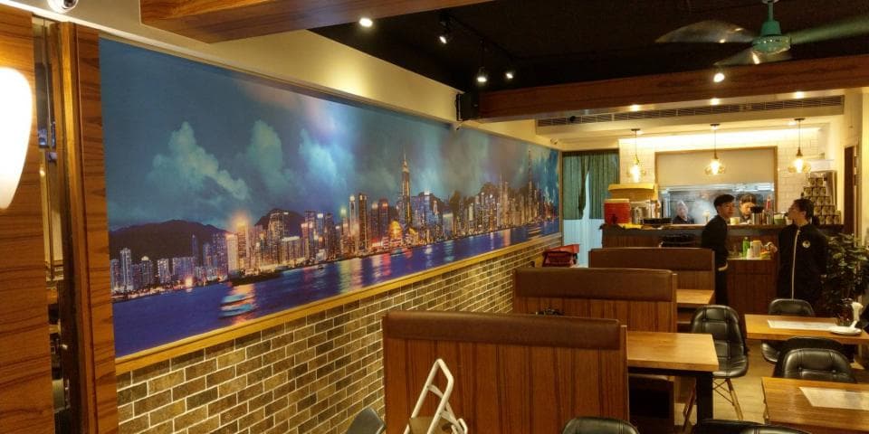 1) 照片顯示了一間裝潢典雅的餐廳,牆上有一幅以香港城市夜景為主題的巨型壁畫,餐廳內部擺放著木製桌椅和吧台,背景還有服務生忙碌的身影