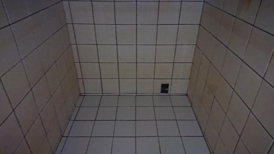 1) 照片顯示一個角落的瓷磚牆壁,由多個方形瓷磚組成,角落有一個插座