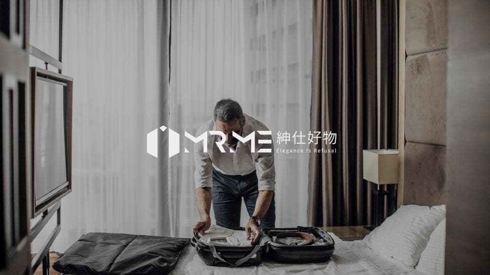 這張照片是一個男人正在整理行李箱,箱子打開放在床上,而他正在檢查裡面的東西。