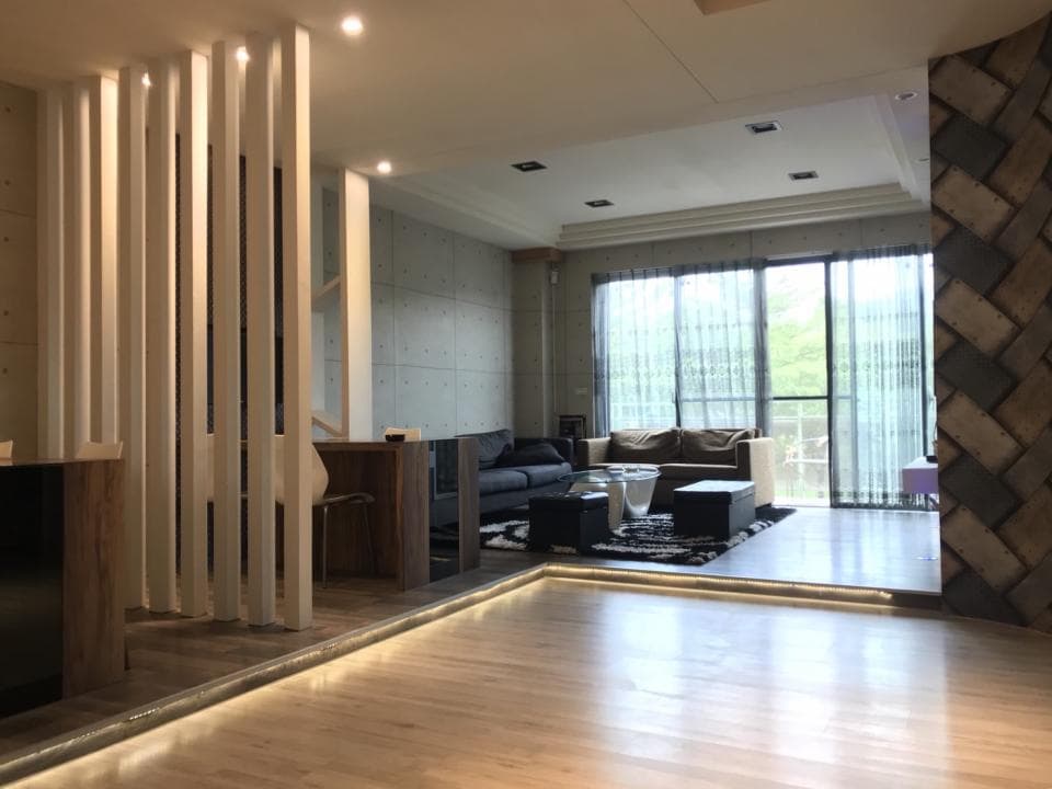 1) 照片顯示一個現代化的客廳,有著木質地板,白色隔板,淺灰色牆面,以及落地窗