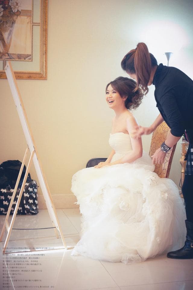 這張照片是一個穿著婚紗的新娘正在鏡子前整理自己的婚紗,她看起來非常開心和興奮,似乎準備好迎接人生中最重要的時刻。