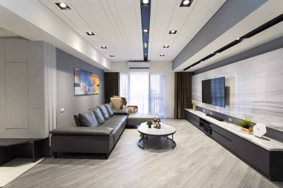 這張「客廳」的照片是一個現代化的客廳,有一個黑色的皮革沙發,一張咖啡桌和一個電視櫃。牆壁上掛著一幅畫,窗戶很大,可以看到外面的風景。