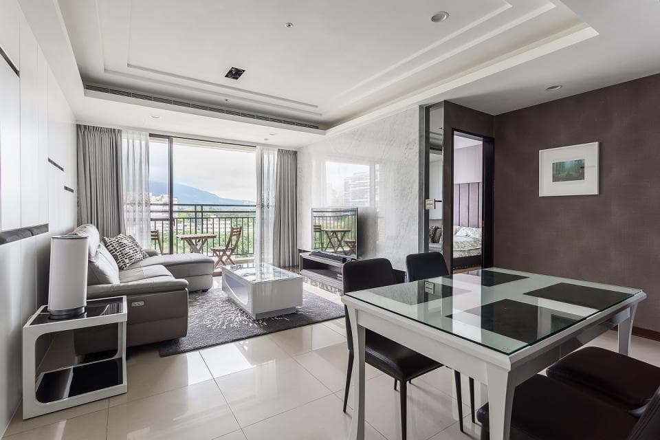 這張「客廳」的照片是現代化的室內設計,空間寬敞明亮,有沙發、電視、餐桌和落地窗,窗外景色宜人。