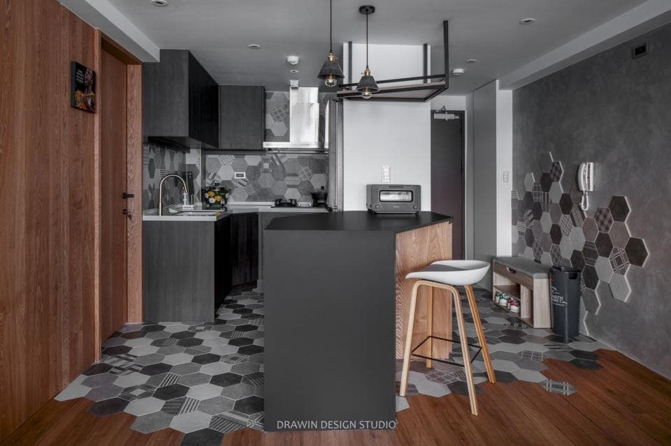 這張照片是一間現代化的廚房,裡面有深色木頭櫥櫃、灰色磁磚,以及一個木質吧檯。吧檯的椅子是白色的,與周圍的深色傢俱形成鮮明的對比,使畫面更有層次感。