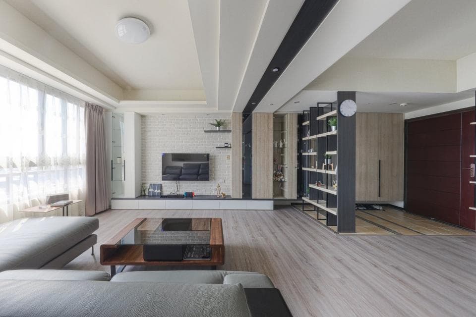 這張照片是一個現代化的客廳,房間裡有一張灰色沙發、一張木質茶几和一個黑色電視櫃。