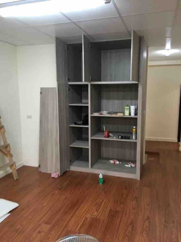 這張照片是一個木質地板的房間,房間裡有一個大型的儲藏櫃,櫃子裡有許多層架,上面擺放着一些物品。