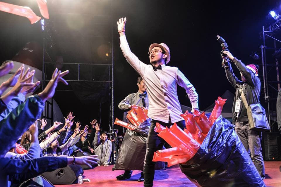 這張照片是一個舞臺表演,照片中最重要的一部分是舞臺上的表演者,他們正在用紅色的氣球進行表演。