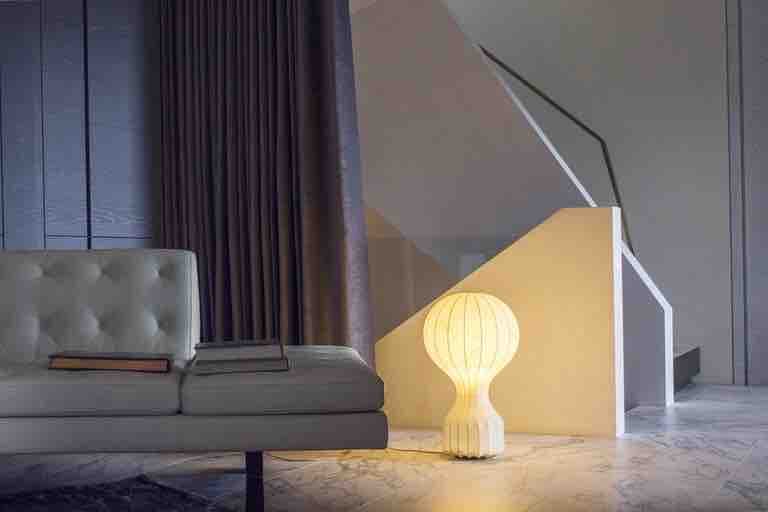 這張「現代客廳」的照片是一張沙發,旁邊放著一盞圓形燈,背景是牆壁和樓梯。