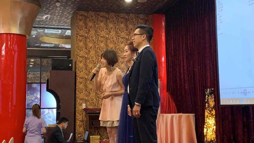 這張「婚禮」的照片是一個新郎和兩個伴娘的合照,新郎穿著西裝,兩個伴娘穿著禮服,背景是婚禮的會場。