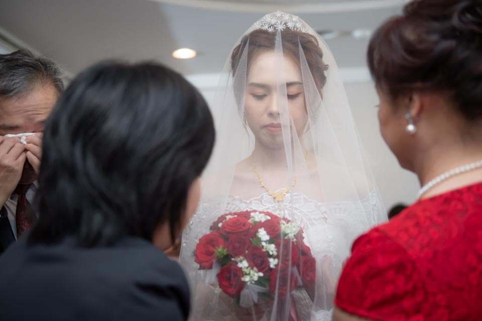 這張照片是一對新人結婚的婚禮現場,新娘穿著婚紗,臉上蒙著頭紗,神情羞怯,新郎眼泛淚光,場面溫馨感人。