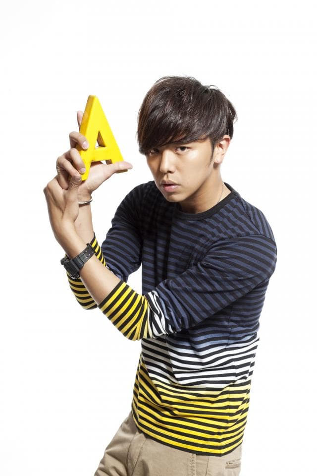 這張照片是一個年輕男子,他穿著藍色和黃色的條紋襯衫,手裡拿著一個黃色的字母 A。