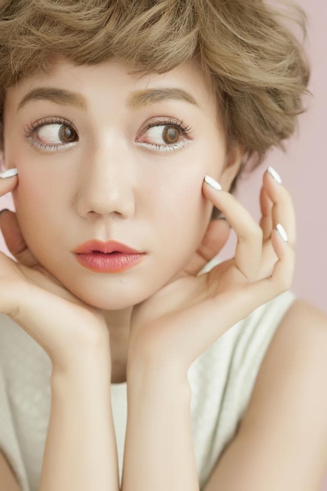 這張「漂亮女性」的照片是,一位短髮女子,她雙手託著下巴,神情自然,展現出她清秀的臉龐和美麗的妝容。