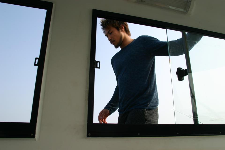 這張「船艙窗戶」的照片是一個男人站在船艙內,他穿著藍色上衣,看起來在看窗外的景色。