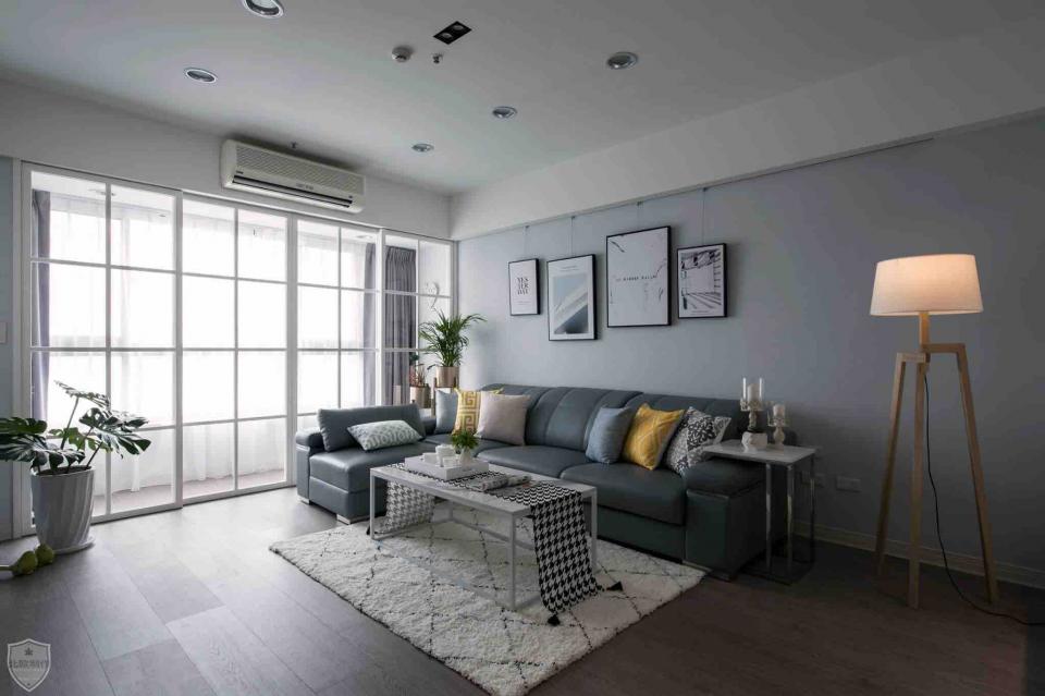 這張客廳的照片是一個現代風格的客廳,裡面有一個灰色沙發、一個白色燈和一個木頭茶几。