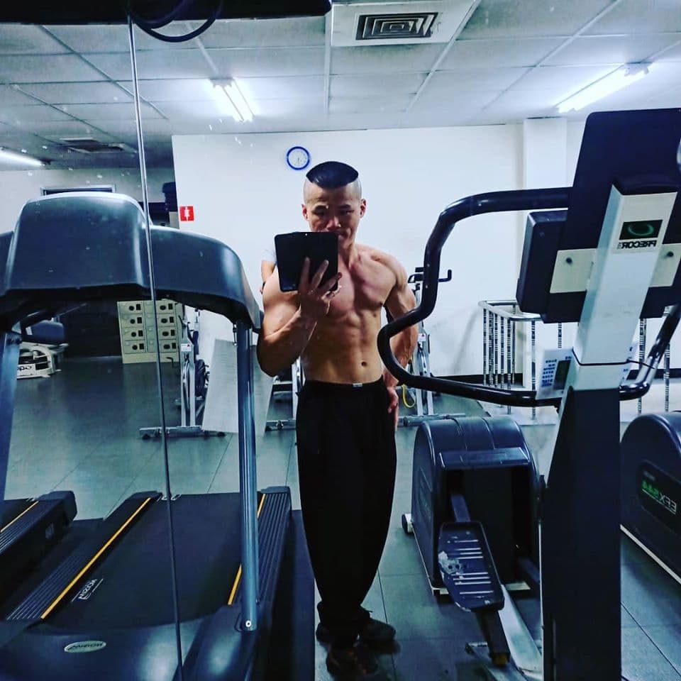 這張「健身房」的照片是一個男人在健身房使用跑步機,他看起來很認真地運動著。他穿著黑色的運動服,看起來很有肌肉。背景是一臺健身器材,看起來很先進。