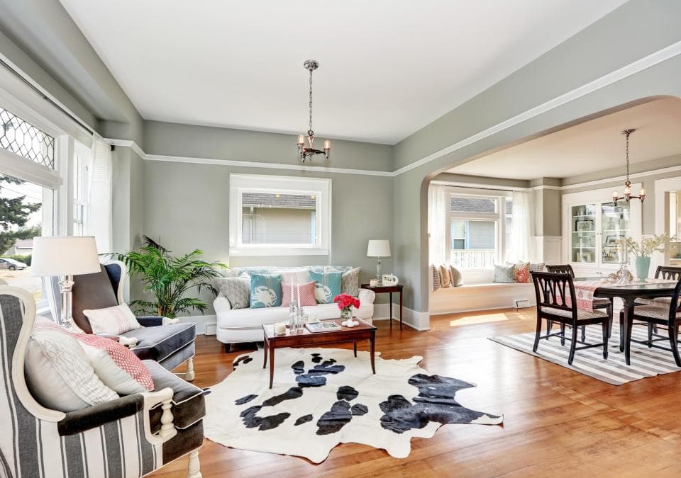 這張「客廳」的照片是 一個明亮寬敞的客廳,有白色沙發、咖啡桌和黑白牛皮地毯。