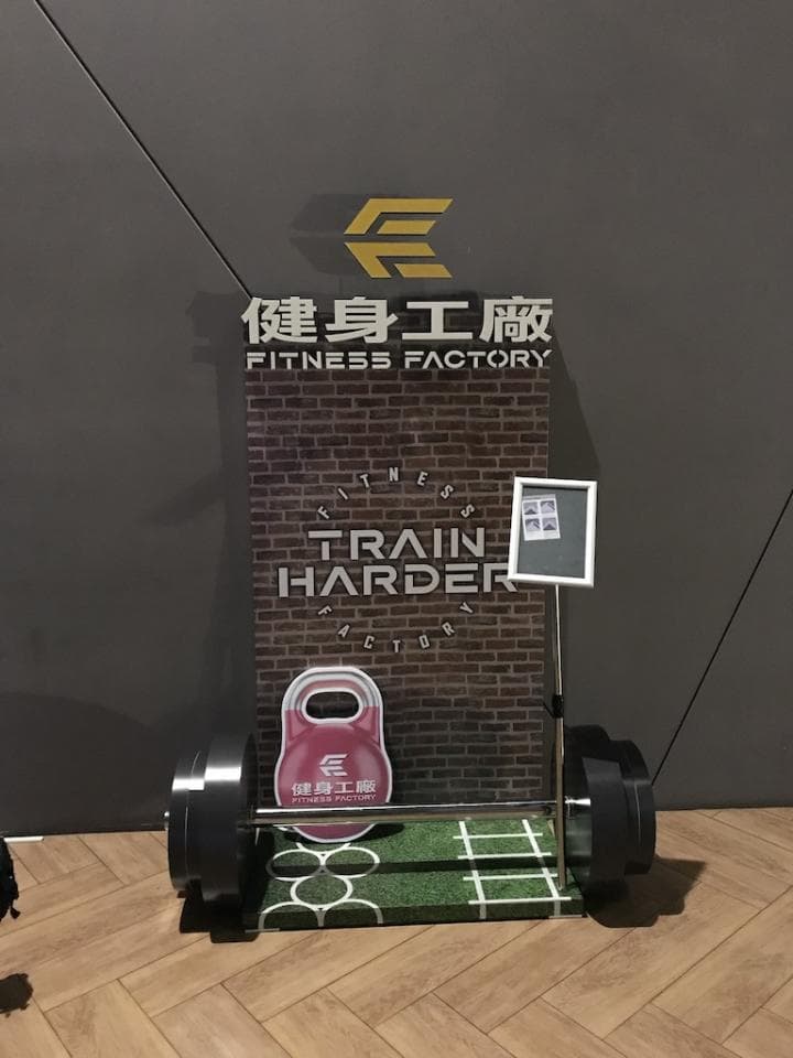 1) 照片顯示一個健身房的標誌和一個裝置,上面有一塊啞鈴和一個標語"訓練更努力"