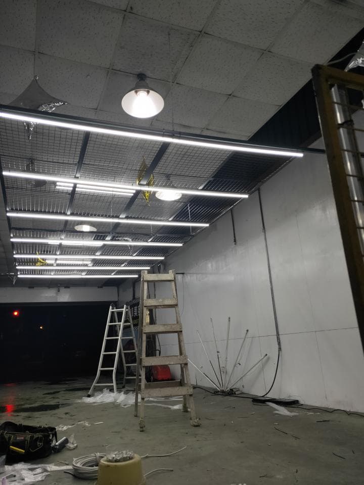 這張照片是一個正在裝修的建築物,天花板上有網狀結構,並且安裝了許多燈管,顯得非常明亮。