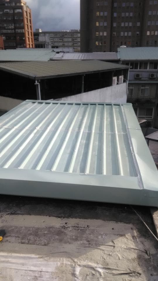 1) 照片顯示一棟建築物屋頂上新裝設的採光罩,採光罩是淺灰色的金屬材質,有條紋設計